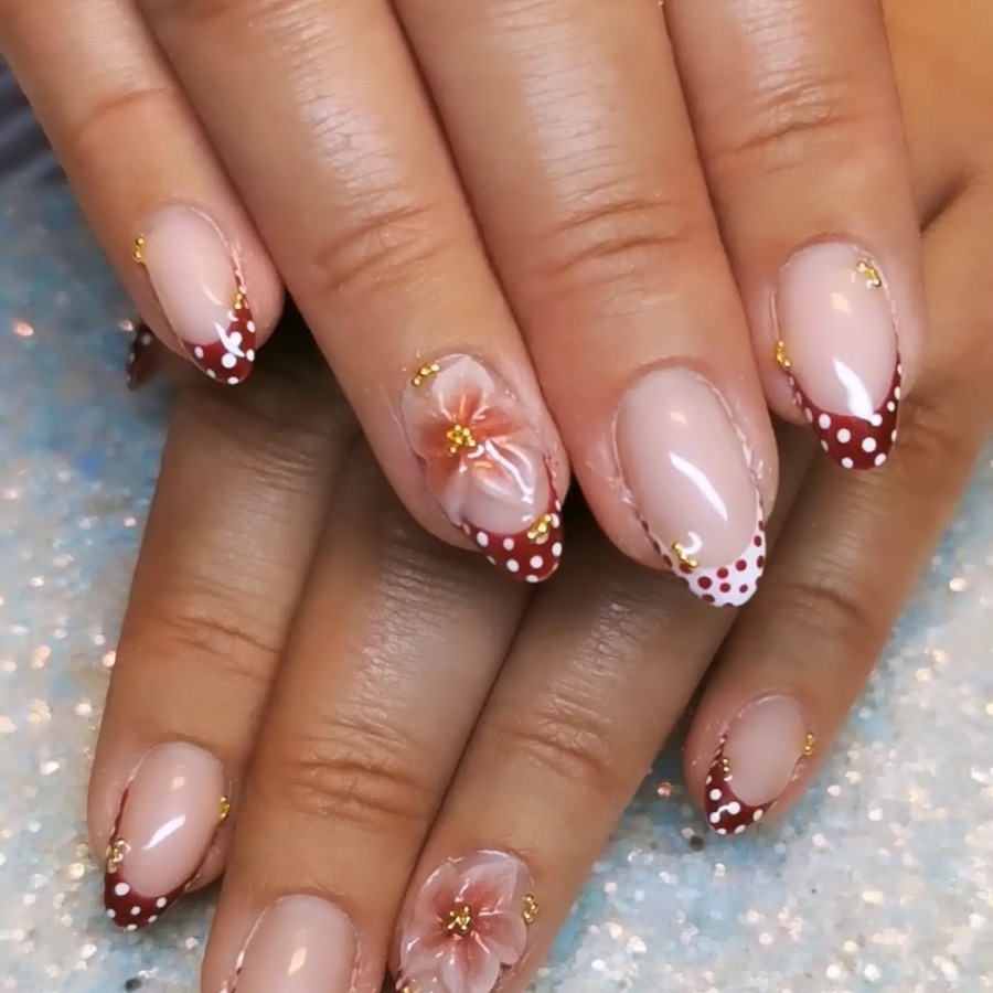 Ongles nude à french bordeaux à pois blancs, fleur peinte et perles dorées